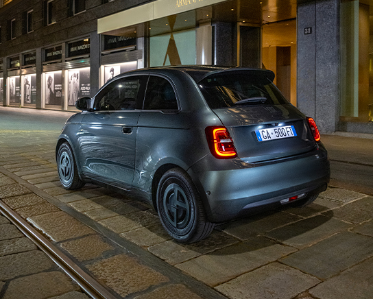 Un ángulo trasero del lado del conductor de un FIAT 500e Edición de Colección Giorgio Armani 2025 verde oscuro.