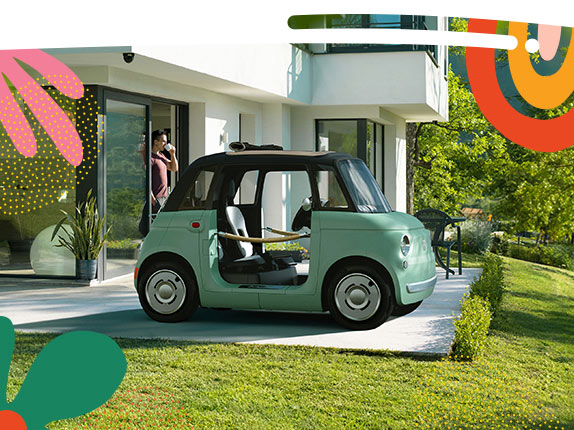 Two mint green preproduction model Fiat Topolino models parked opposite of each other on a golf course at sunset. On the left, a Topolino Dolce Vita with door ropes and a rolled-up soft top, and on the right a Topolino.