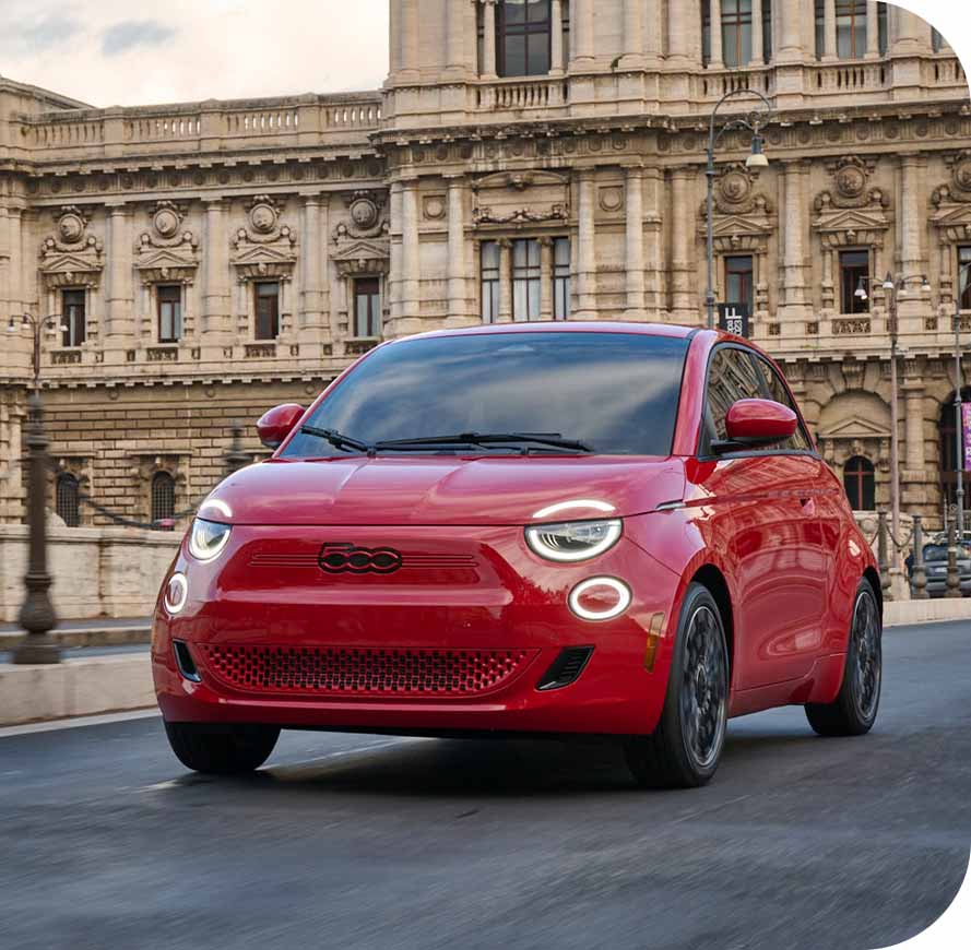 Vista frontal de un Fiat 500e rojo de 2024, inspirado en una calle de la ciudad.