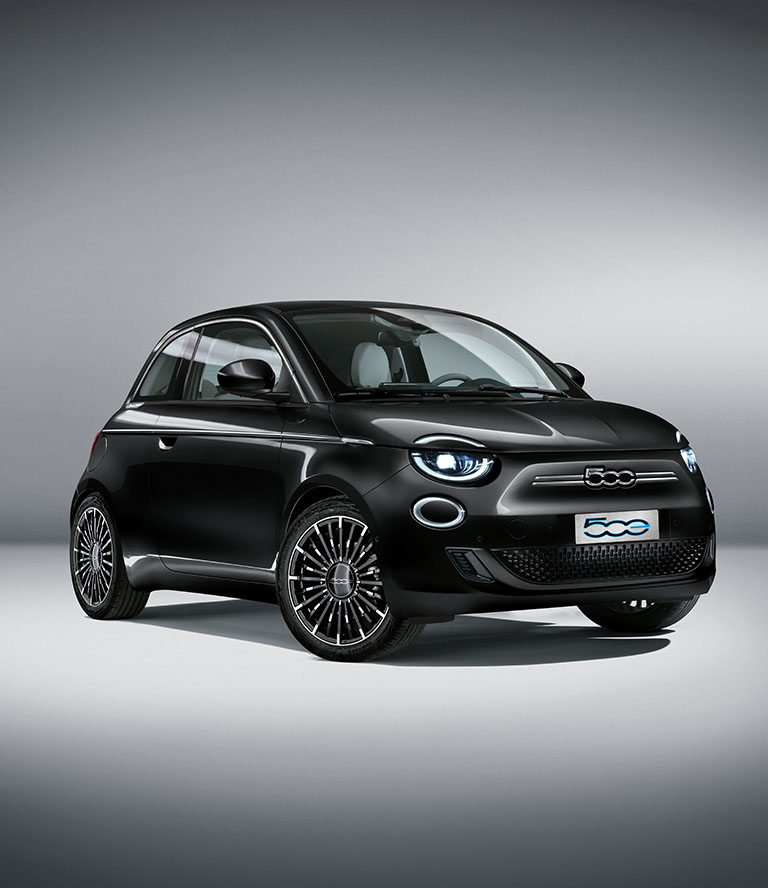 Perfil frontal en ángulo, del lado del pasajero, de un Fiat 500e La Prima negro, modelo europeo, de 2024, en un estudio.